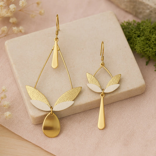 Boucles d’oreilles pendantes longues dépareillées, cuir texturé champagne clair et blanc, inspiration feuilles et ailes, bijou artisanal haut de gamme.